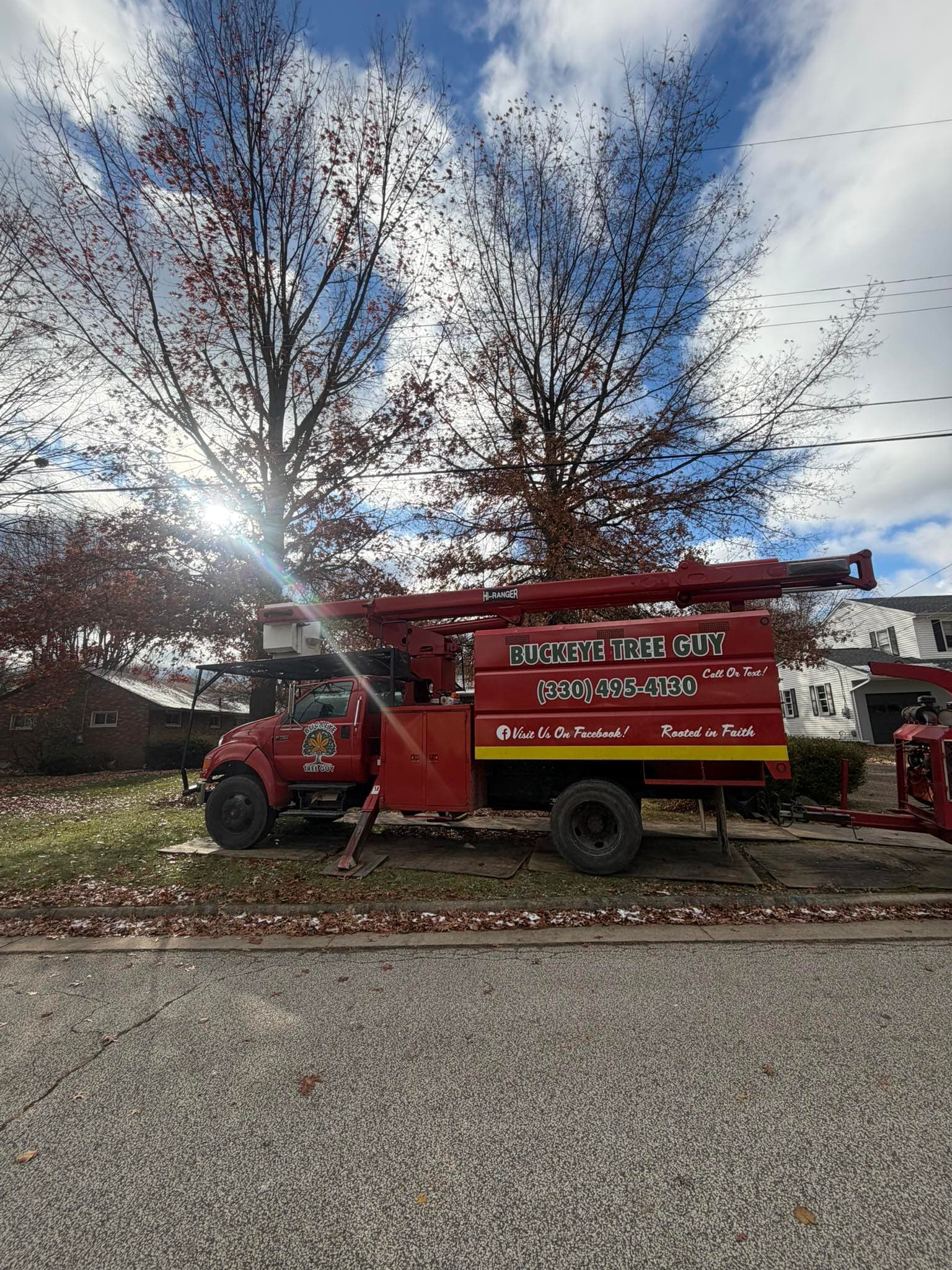 Buckeye Tree Guy company truck with boom crane on a job site
